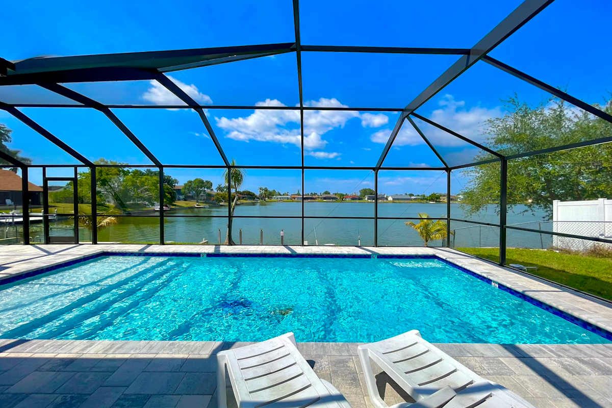 Screened heated pool and sun loungers overlooking the lake at Lakeside Haven, Cape Coral